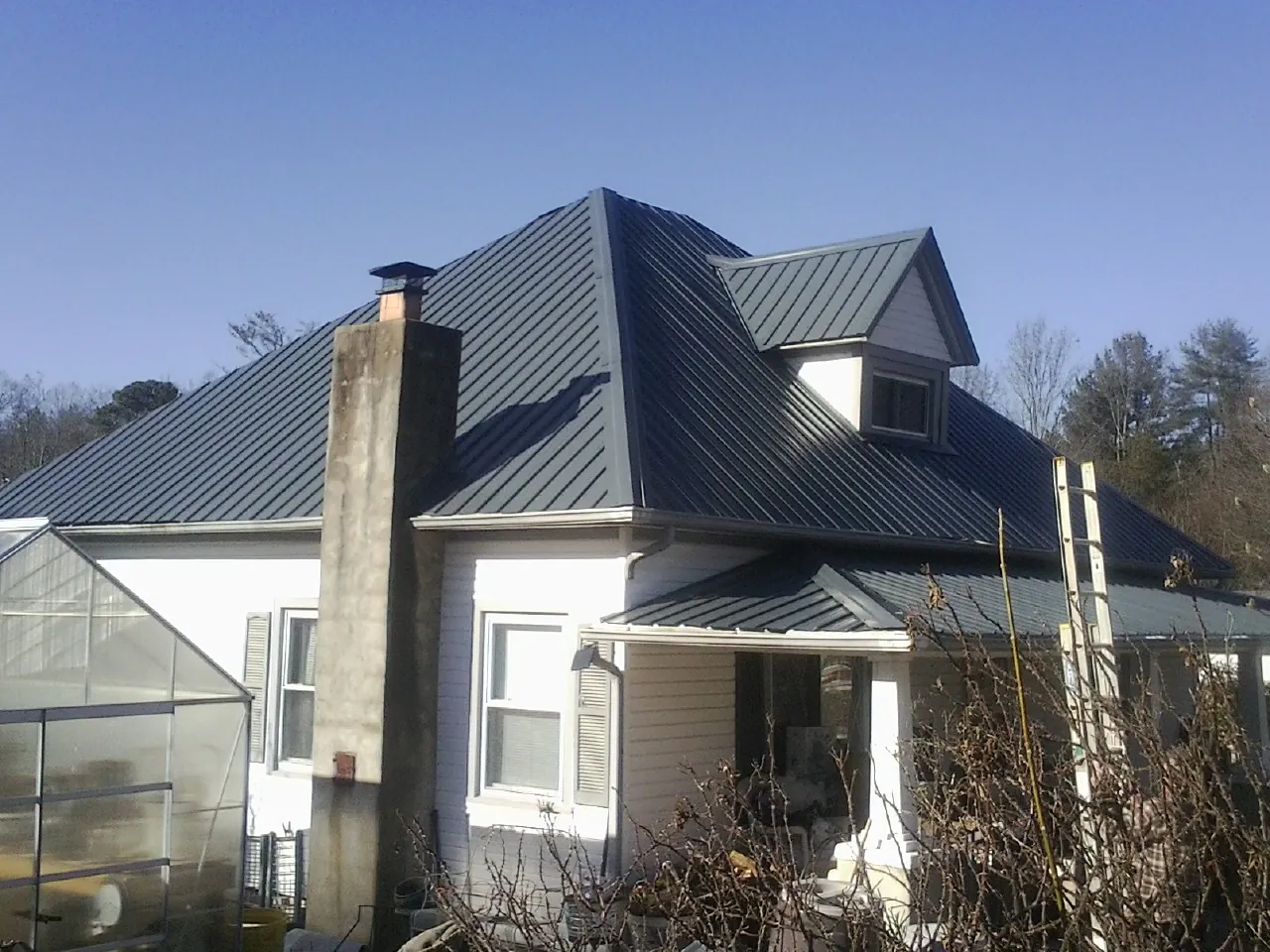 Dark blue standing seam metal roof on a white farmhouse with dormer — Slate & Tile Roof Repair by Roofing Brothers in Mertztown