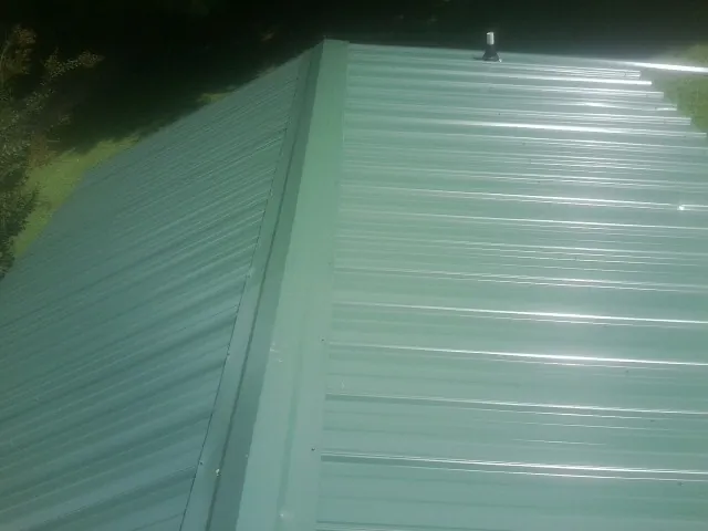 New green metal panels meeting at the ridge of a roof — Flat Roof Repair work by our crew in Mertztown