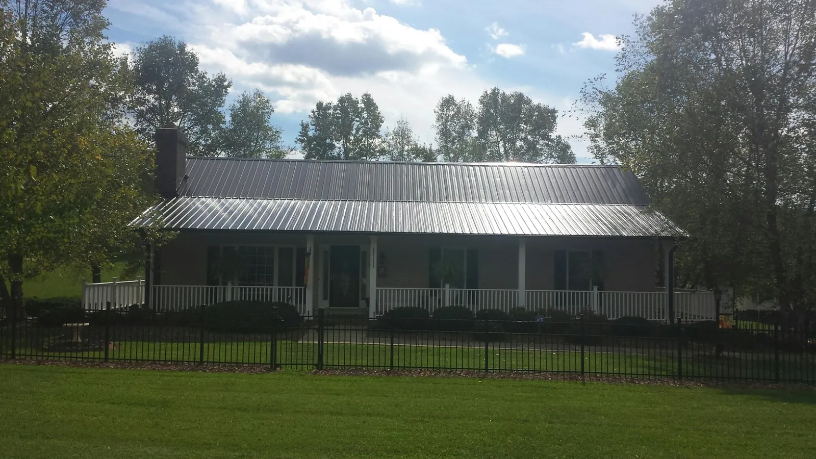 Gray metal roof on a brick ranch with a full width front porch — Gutter Guard Installation work by our crew in Mertztown
