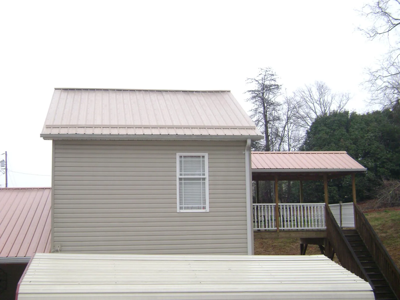 Tan metal roofs on a two story addition and attached porch, from a Roof Replacement job in Mertztown