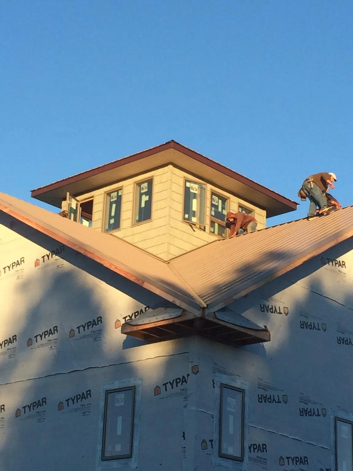 Roofers working around a rooftop cupola on a new metal roof at sunset — Roof Waterproofing in Mertztown by Roofing Brothers